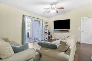 Living room with ceiling fan, lofted ceiling, and dark hardwood / wood-style floors