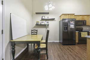 Kitchen featuring stainless steel refrigerator with ice dispenser, dark hardwood / wood-style flooring, black range with electric cooktop, a chandelier, and pendant lighting