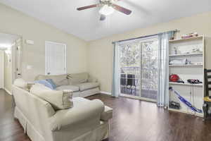 Living room with ceiling fan, vaulted ceiling, and dark hardwood / wood-style floors