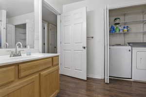 Bathroom with washer and dryer, wood-type flooring, and vanity