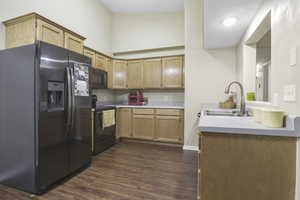 Kitchen featuring dark wood-type flooring, sink, and black appliances