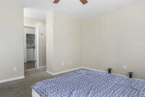 Carpeted bedroom featuring ceiling fan and washer / dryer