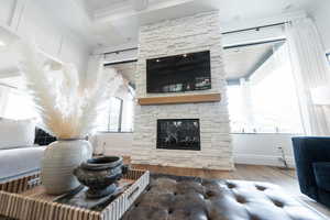 Living room featuring crown molding, wood finished floors, and a stone fireplace