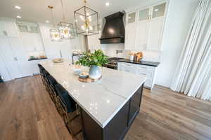 Kitchen with custom range hood, recessed lighting, decorative backsplash, wood finished floors, and high end stainless steel range oven