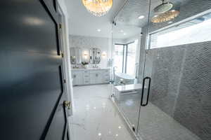 Bathroom with marble tiled floors, double vanity, a stall shower, recessed lighting, and a chandelier