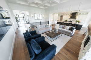 Living room featuring beamed ceiling, coffered ceiling, a high ceiling, dark wood-type flooring, and a chandelier