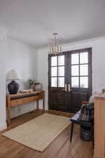 Foyer featuring hardwood / wood-style flooring, ornamental molding, french doors, and an inviting chandelier