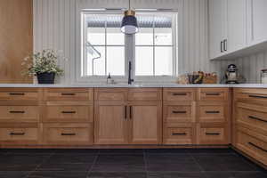 Kitchen featuring sink, dark tile patterned flooring, and hanging light fixtures