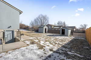 Snowy yard featuring two storage sheds