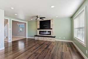 Unfurnished living room featuring a healthy amount of sunlight, a fireplace, and dark hardwood / wood-style floors