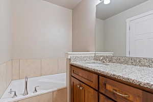 Bathroom featuring vanity and a relaxing tiled tub