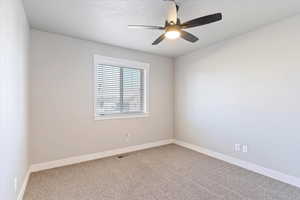 Spare room featuring ceiling fan and carpet