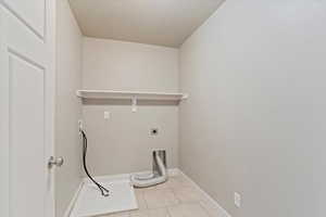 Laundry room featuring light tile patterned floors, washer hookup, electric dryer hookup, and a textured ceiling