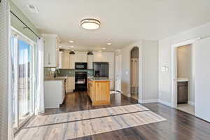 Kitchen with range, a kitchen island, dark wood-type flooring, sink, and stainless steel fridge