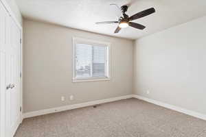 Unfurnished bedroom with ceiling fan, a textured ceiling, and carpet flooring