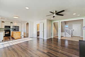 Kitchen with black appliances, white cabinets, dark hardwood / wood-style flooring, and a kitchen island