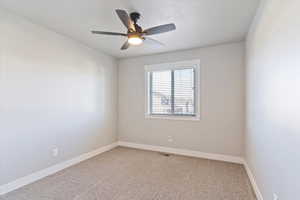 Carpeted empty room featuring ceiling fan