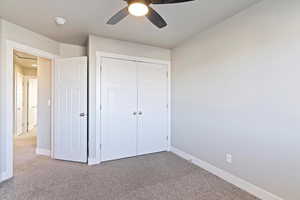 Unfurnished bedroom featuring ceiling fan, a closet, and carpet flooring