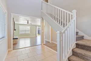 Stairway featuring ceiling fan, plenty of natural light, and tile patterned flooring