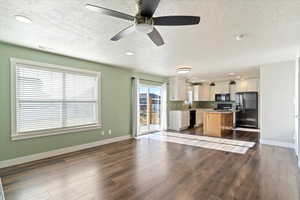 Kitchen featuring hardwood / wood-style floors, white cabinets, black appliances, a center island, and a textured ceiling