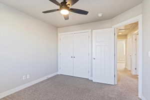 Unfurnished bedroom with ceiling fan, light colored carpet, and a closet