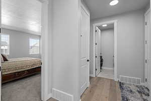 Hall with a textured ceiling and light hardwood / wood-style flooring