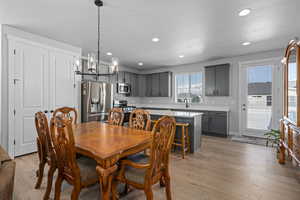 Dining area with light hardwood / wood-style floors, sink, and an inviting chandelier