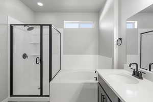 Bathroom featuring a wealth of natural light, shower with separate bathtub, and vanity