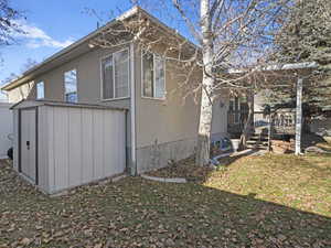 View of home's exterior with a storage shed, a wooden deck, and a lawn