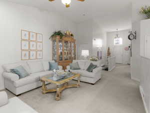 Living room featuring light colored carpet, vaulted ceiling, and ceiling fan with notable chandelier