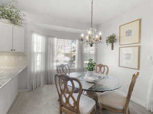 Dining space with light carpet and an inviting chandelier