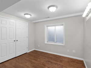 Unfurnished bedroom with a closet and dark wood-type flooring