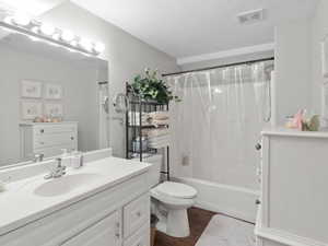 Full bathroom featuring toilet, vanity, wood-type flooring, a textured ceiling, and shower / tub combo with curtain