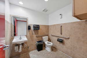 Bathroom with sink, toilet, and tile walls