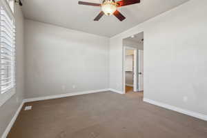 Carpeted spare room featuring ceiling fan