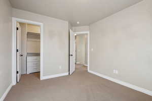 Unfurnished bedroom with light carpet, a closet, and a spacious closet