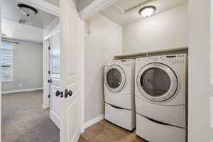 Clothes washing area featuring washer and dryer and light carpet