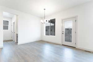 Unfurnished dining area featuring an inviting chandelier and hardwood / wood-style floors