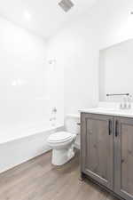 Full bathroom featuring vanity, hardwood / wood-style floors, bathing tub / shower combination, and toilet