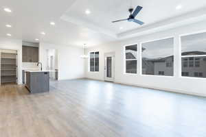 Unfurnished living room featuring sink, ceiling fan with notable chandelier, and hardwood / wood-style floors