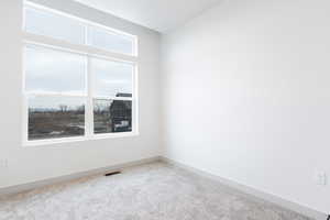 Carpeted spare room with lofted ceiling