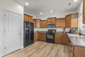 Kitchen with sink, black & stainless appliances, and light LVP flooring