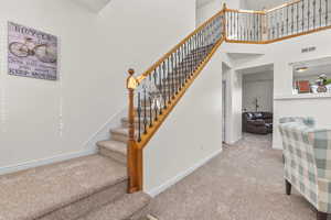 Stairs with carpet flooring and a towering ceiling