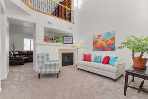 Carpeted living room with a high ceiling and a tile fireplace