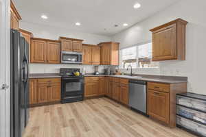 Kitchen with sink, black & stainless appliances, and light LVP flooring