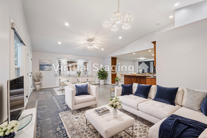 Living room featuring vaulted ceiling and ceiling fan with notable chandelier