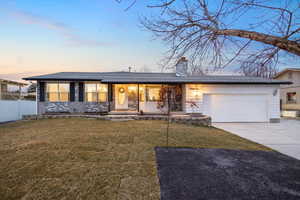 Single story home featuring a garage and a lawn