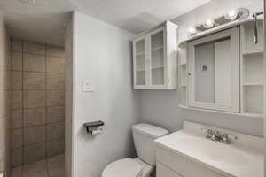 Bathroom with toilet, a tile shower, and vanity