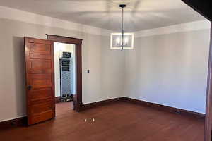 Unfurnished dining area featuring dark hardwood / wood-style floors and an inviting chandelier