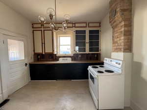 Kitchen featuring decorative backsplash, white electric range oven, a notable chandelier, hanging light fixtures, and sink